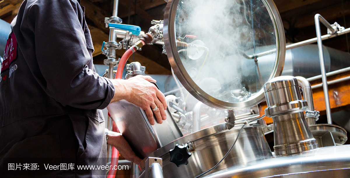 酿酒师在小啤酒厂制造精酿啤酒,将原料倒入蒸笼中